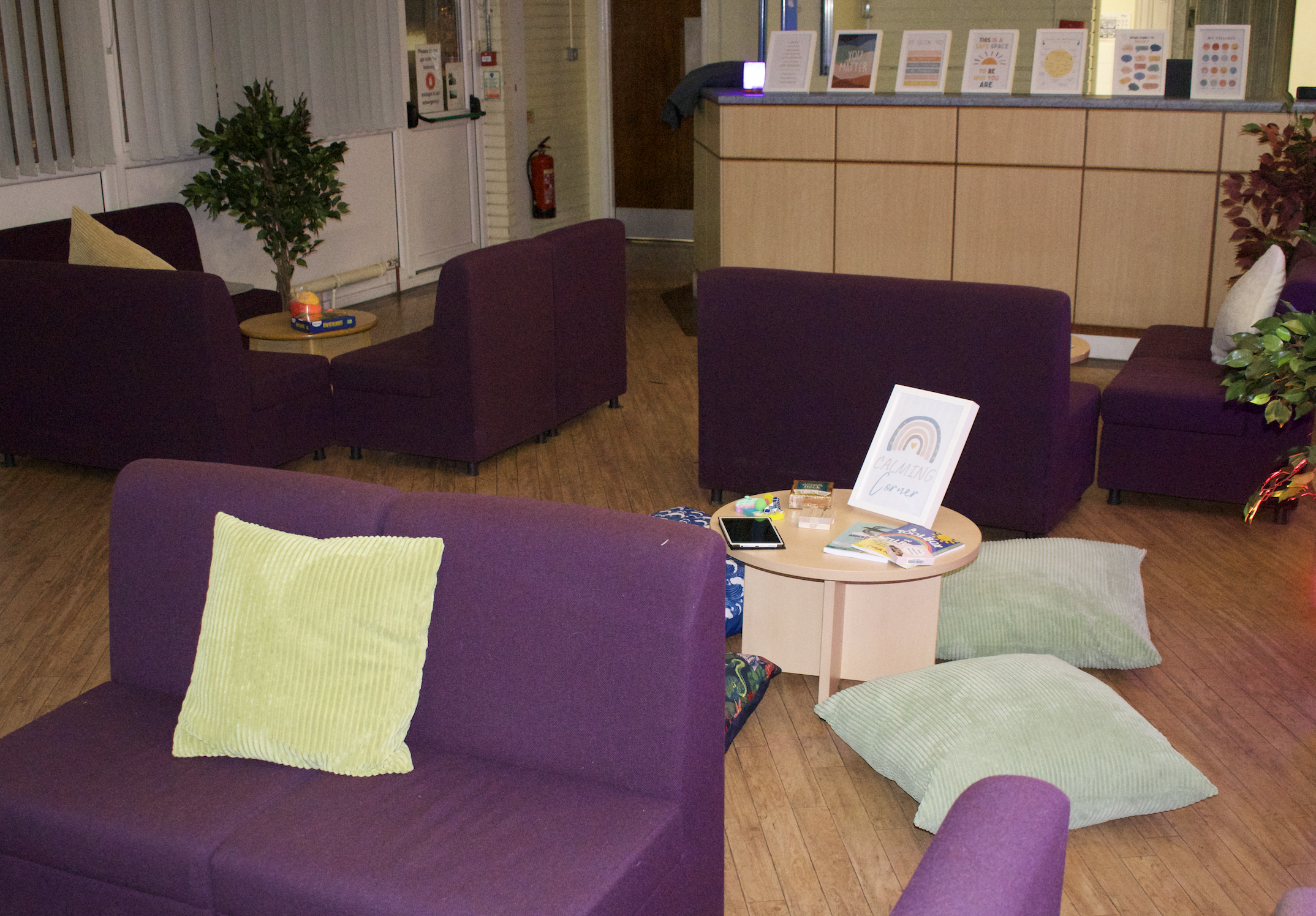 the photo shows a room full of small sofas, cushions and small tables that contain fidget toys and books